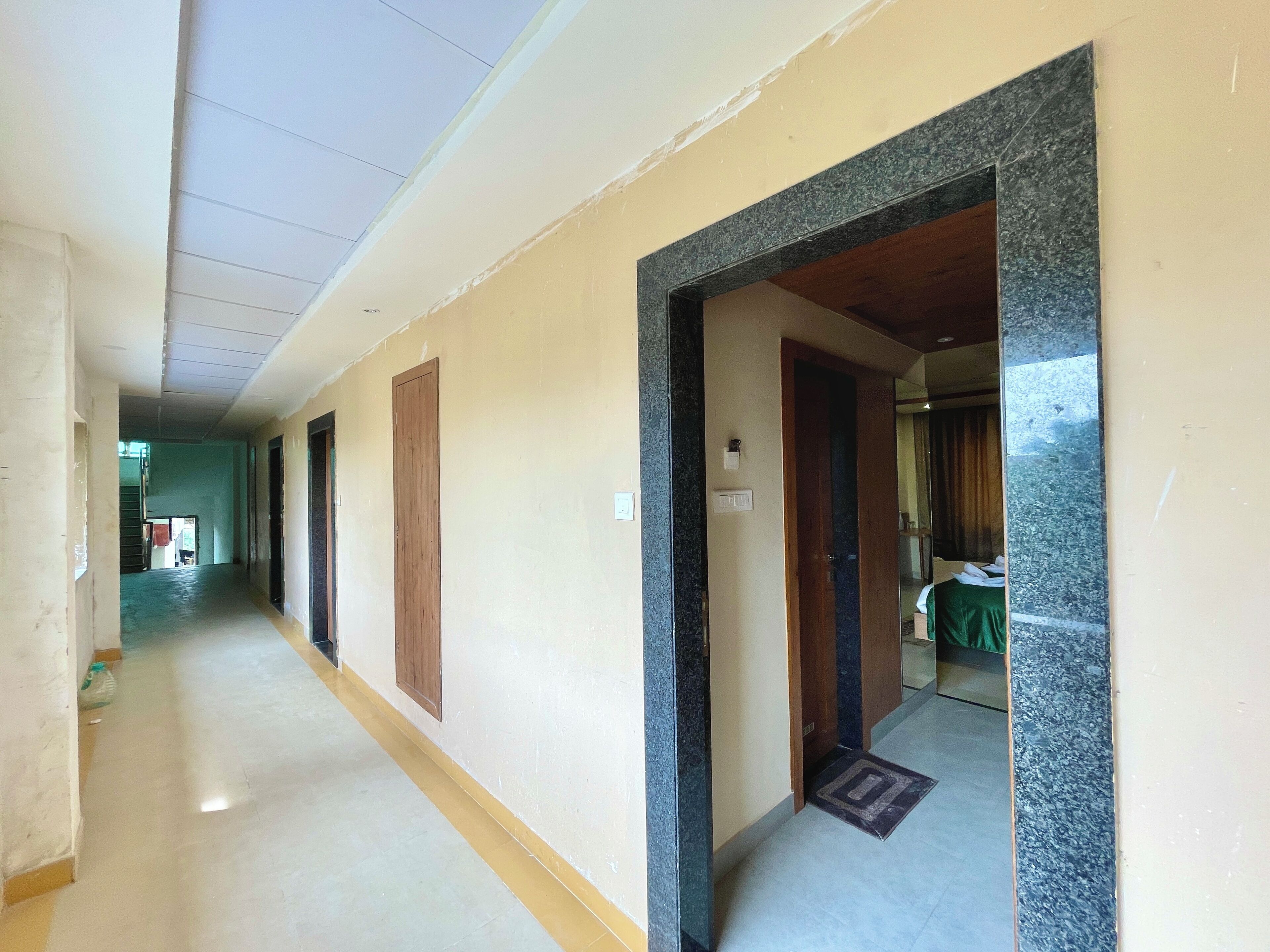 A long corridor with doors on both sides, a tiled floor, and a ceiling with recessed lighting.