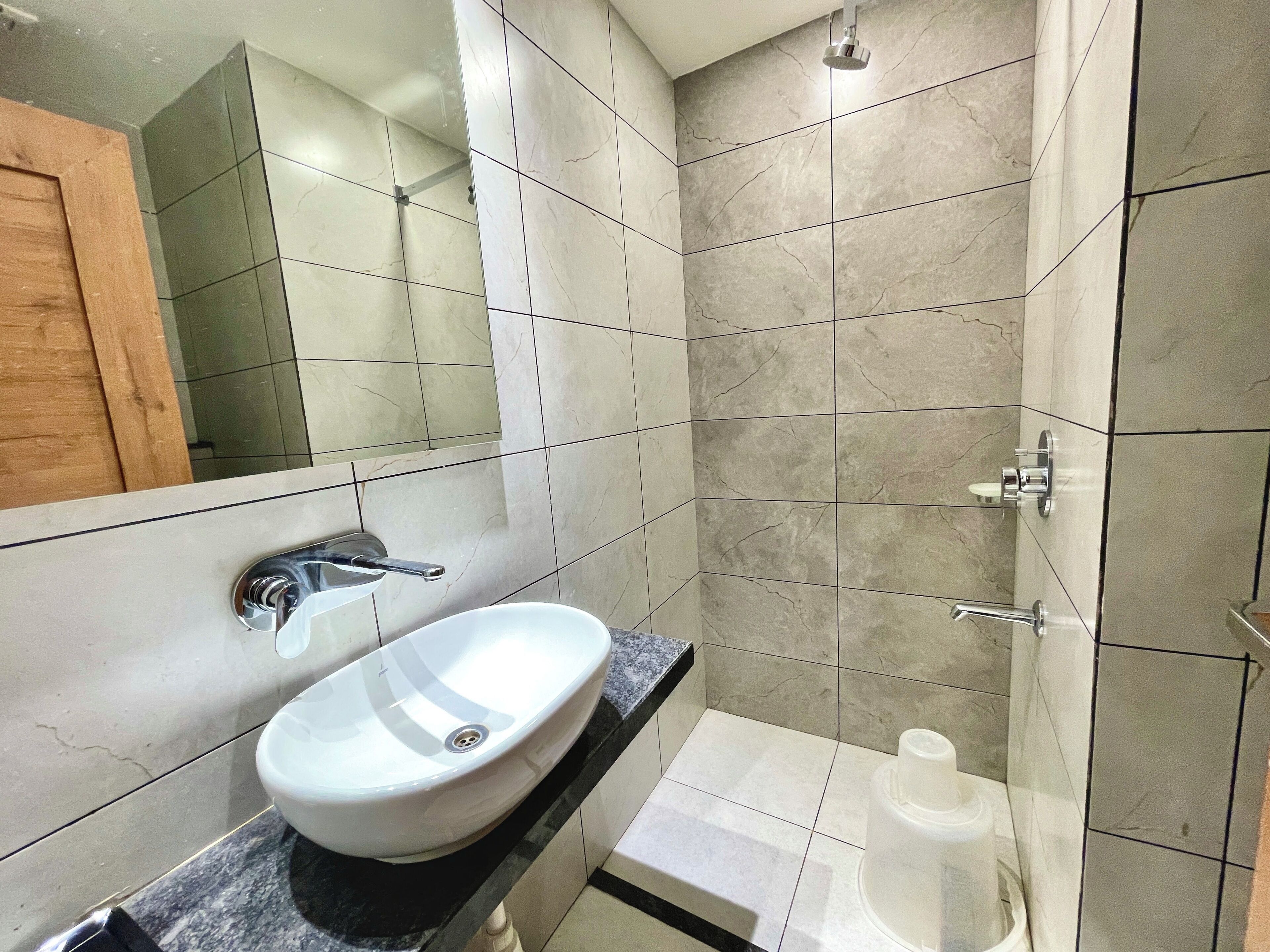 Un baño con lavamanos blanco, espejo y ducha.