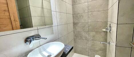 A bathroom with a white sink, a mirror, and a shower.