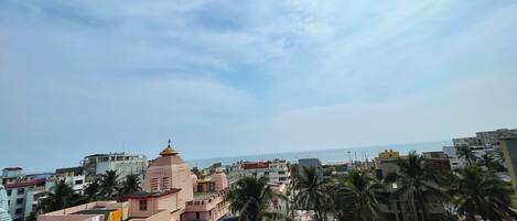 A coastal cityscape with a prominent pink building, likely a religious or cultural site, and a clear view of the sea.