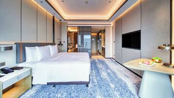 A modern hotel room with a large bed, a desk, a flat-screen TV, and a small dining table.
