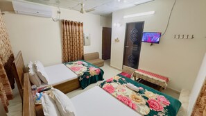 Una habitación de hotel con dos camas, televisor, escritorio y silla.