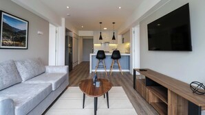 A modern living room with a grey sofa, a wooden coffee table, and a TV mounted on the wall. - w* | Fabulous 2BR w/ Balcony in Miraflores (Miraflores)
