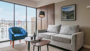 A modern living room with a grey sofa, a blue armchair, and a small table. - w* | Fabulous 2BR w/ Balcony in Miraflores (Miraflores)