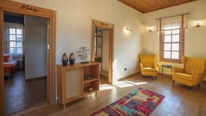 A spacious living room with wooden flooring, a colorful rug, and two yellow armchairs. - Oldies Hotel Bistro Restaurant (Antalya)