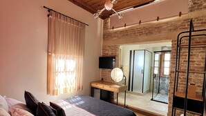 A bedroom with a bed, wooden ceiling, a small desk, a mirror, and a bathroom visible through an open door. - Oldies Hotel Bistro Restaurant (Antalya)