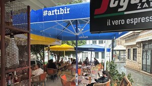 An outdoor café with tables and chairs, umbrellas, and a sign for 'Segafredo Zanetti il vero espresso'. - Oldies Hotel Bistro Restaurant (Antalya)