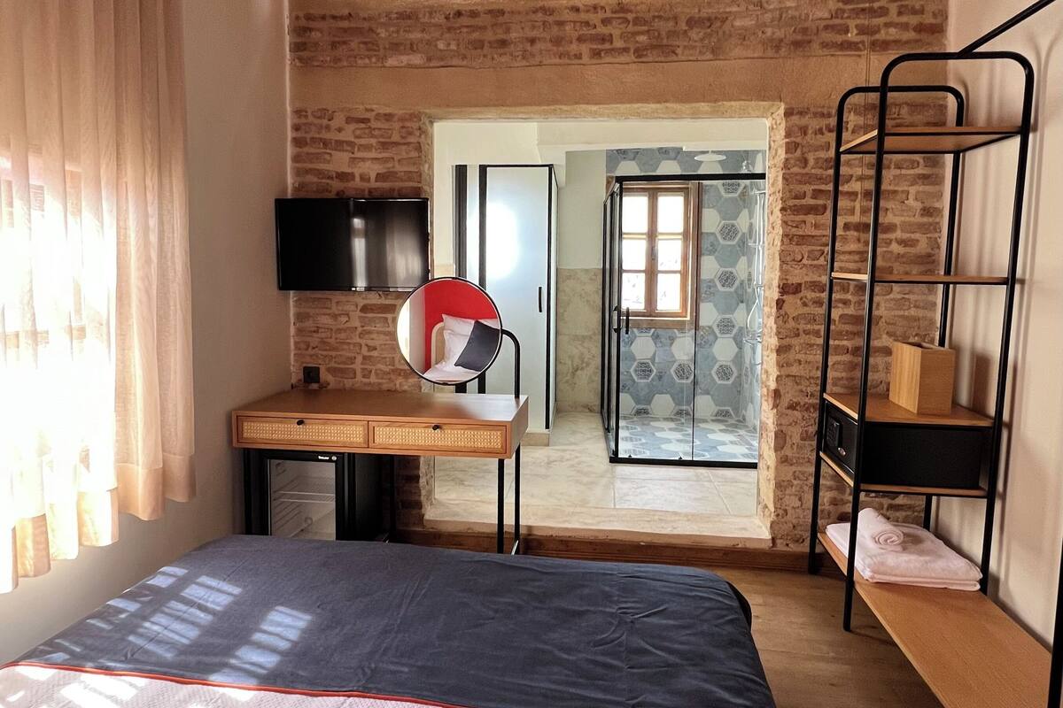 Una habitación con cama, escritorio, televisor y literas.