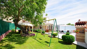 A well-maintained garden with a swing set, neatly trimmed hedges, and a patio area with outdoor furniture. - Charming 3-bedroom house with private pool and beautiful garden (Šajini)