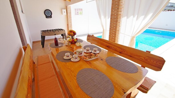 A dining area with a wooden table set for breakfast, including plates, cups, and a fruit bowl. - Charming 3-bedroom house with private pool and beautiful garden (Šajini)