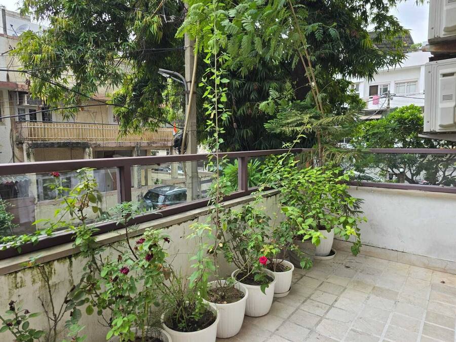 Un balcón con plantas en macetas y vistas a una calle con edificios y coches.