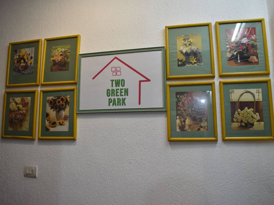 Una pared con fotografías florales enmarcadas y un cartel central que dice "TWO GREEN PARK".