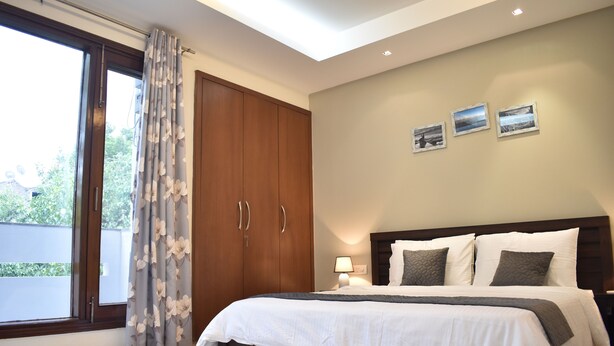 Un dormitorio con una cama grande, un armario de madera y una puerta corrediza de vidrio al exterior.