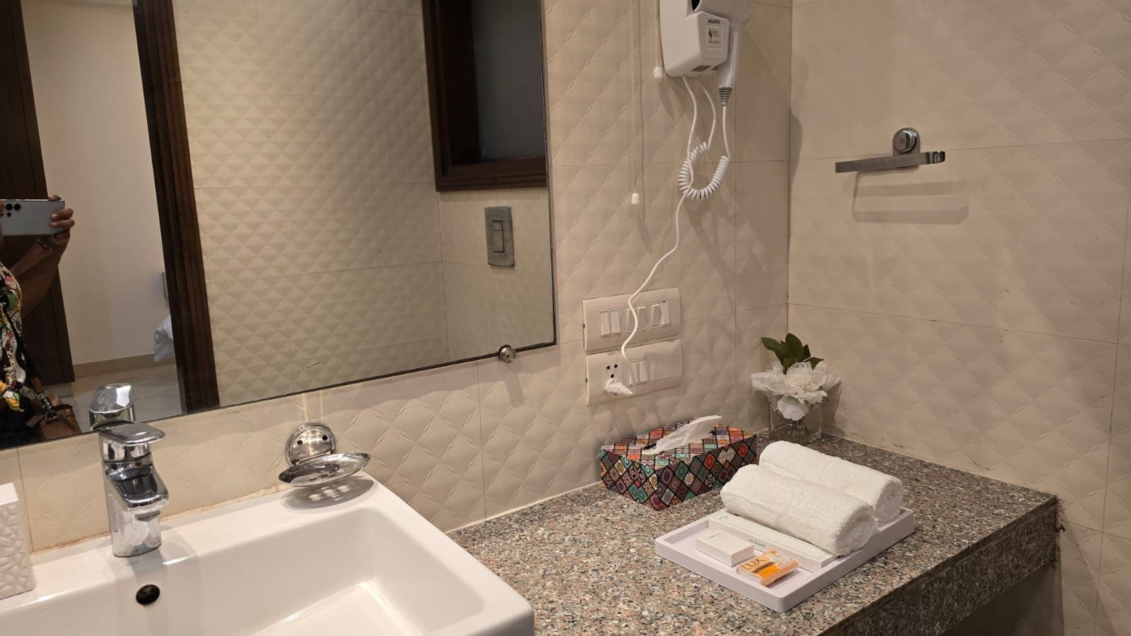 A bathroom with a sink, mirror, towel rack, and a tissue box.