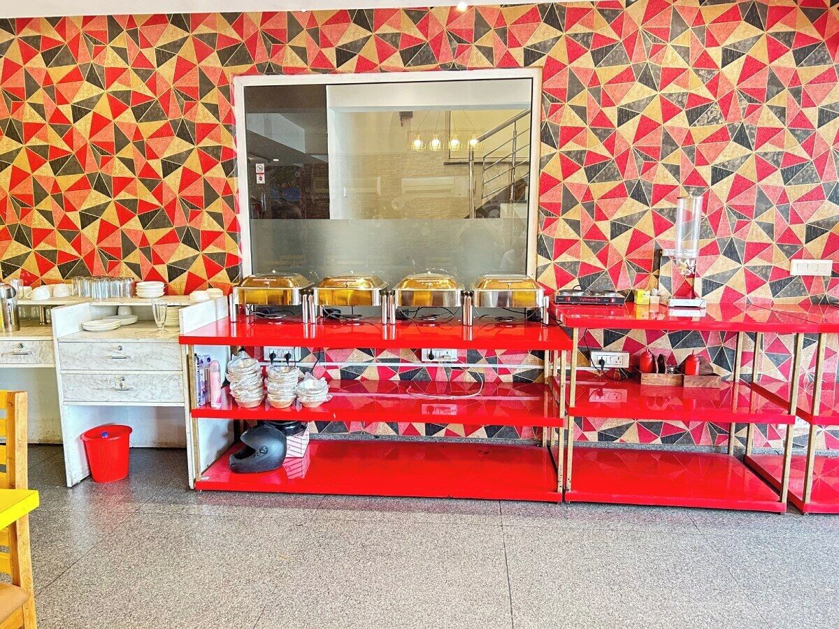 A kitchen area with a red counter, a large window, and a patterned wall.