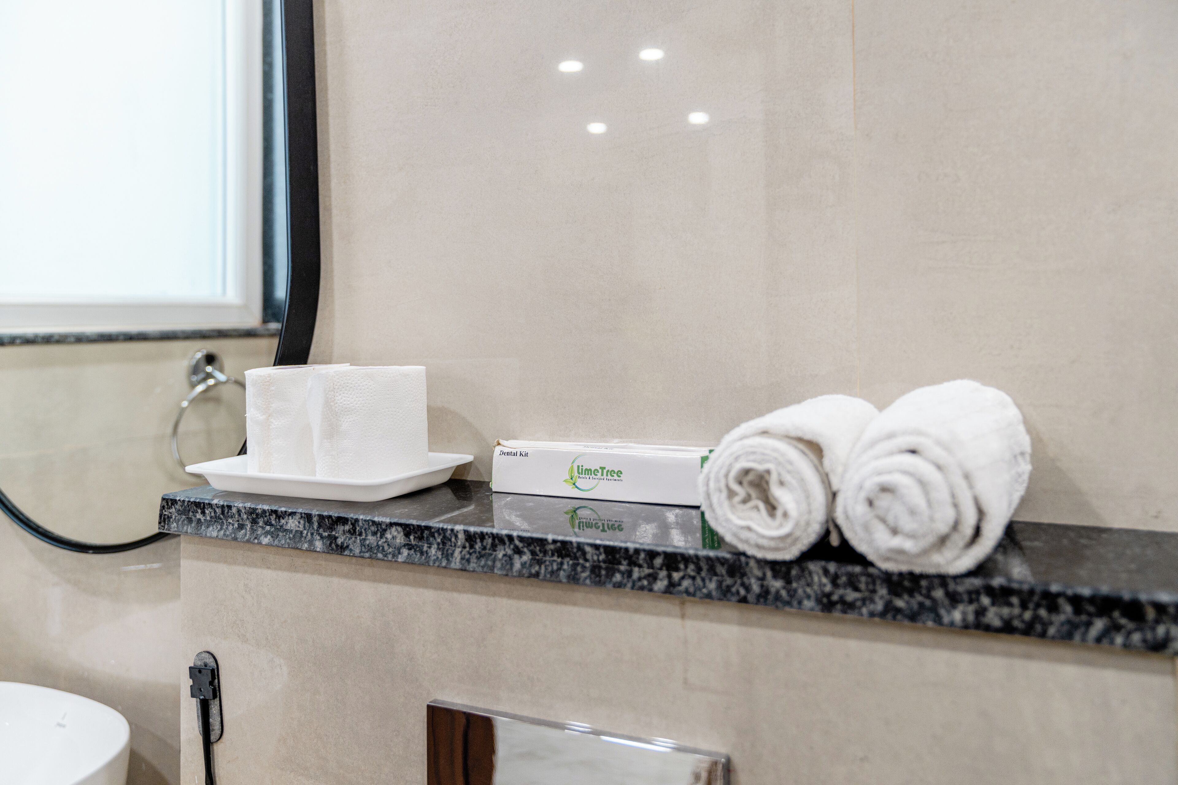 Une salle de bain dotée d’un comptoir en marbre, d’une trousse de toilette et de serviettes roulées.