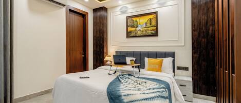 A modern bedroom with a bed, bedside table, lamp, laptop, and a painting on the wall.