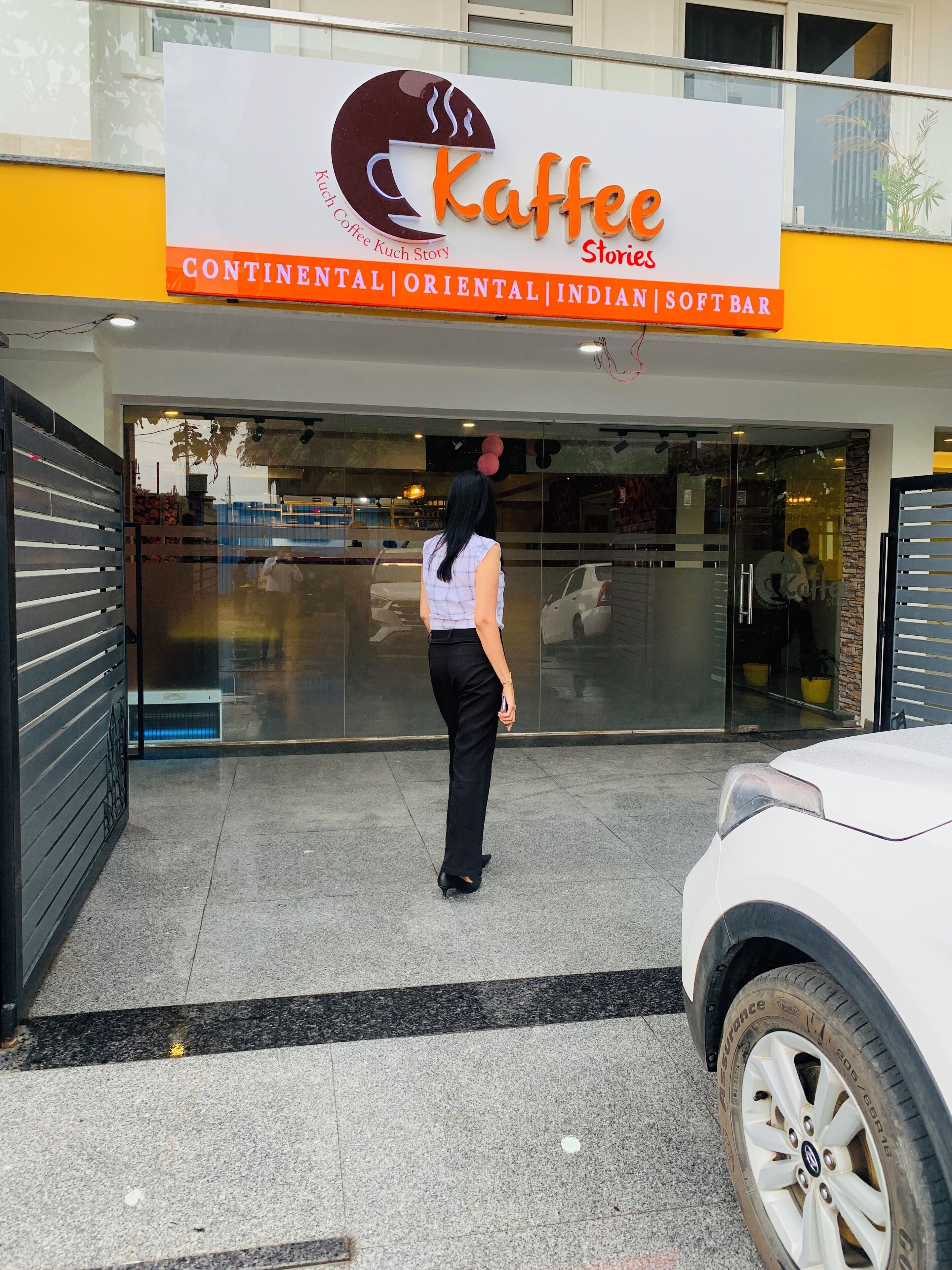 A coffee shop named 'Kaffe Stories' with a signboard indicating it offers continental, oriental, Indian, and soft bar services.