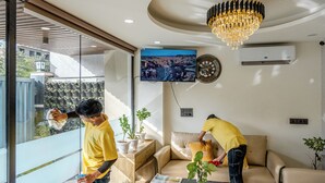 A modern living room with a glass wall, a sofa, a coffee table, and a chandelier. - Street Studio by Lime Tree Hotels (Gurugram)