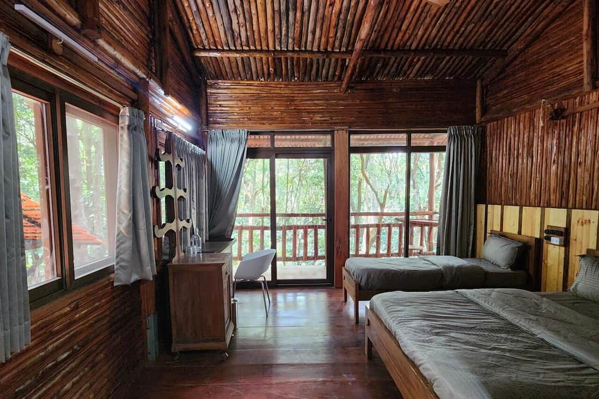 Eine Holzhütte mit Holzwänden und -böden, zwei Betten, einem Schreibtisch und einem Stuhl.