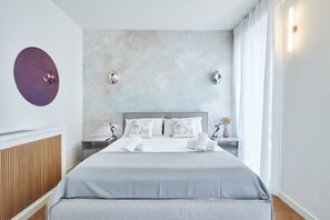 A modern bedroom with a large bed, a wooden radiator, and a textured wall.