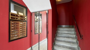 A staircase with a red wall and a wooden storage unit with multiple drawers.