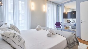 A modern bedroom with a large bed, a desk, and a mirror.