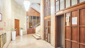 A lobby with marble flooring, a staircase, wooden paneling, and potted plants. - Easylife - Refined apartment in Duomo (Milano)