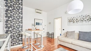 A modern living room with a sofa, a dining area with a table and chairs, and a kitchen area with a stove. - Easylife - Refined apartment in Duomo (Milano)