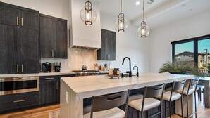 A modern kitchen with dark cabinetry, a marble island, and pendant lighting. - Townhome w/Hot Tub | Walk to Ski Lift (Park City)