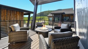 A covered outdoor seating area with wicker furniture and a fire pit. - Townhome w/Hot Tub | Walk to Ski Lift (Park City)
