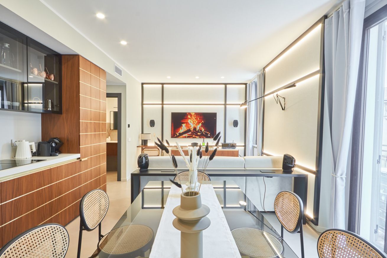 A modern dining area with a long table, chairs, and a vase with decorative elements.