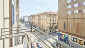 A city street with buildings, a pedestrian bridge, and a tram line.