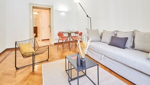 Un salon moderne comprenant un canapé, un fauteuil, une table à manger avec des chaises et un lampadaire.
