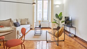 Un salon moderne avec un canapé, une table basse, un meuble pour la télévision et une plante.