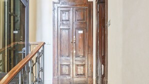 Une porte double en bois, avec une main courante en métal et des panneaux de verre sur le côté gauche.