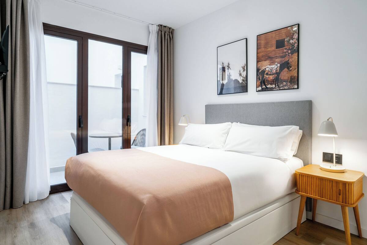 Ein Hotelzimmer mit einem großen Bett, einem Nachttisch mit Lampe und zwei gerahmten Bildern an der Wand.