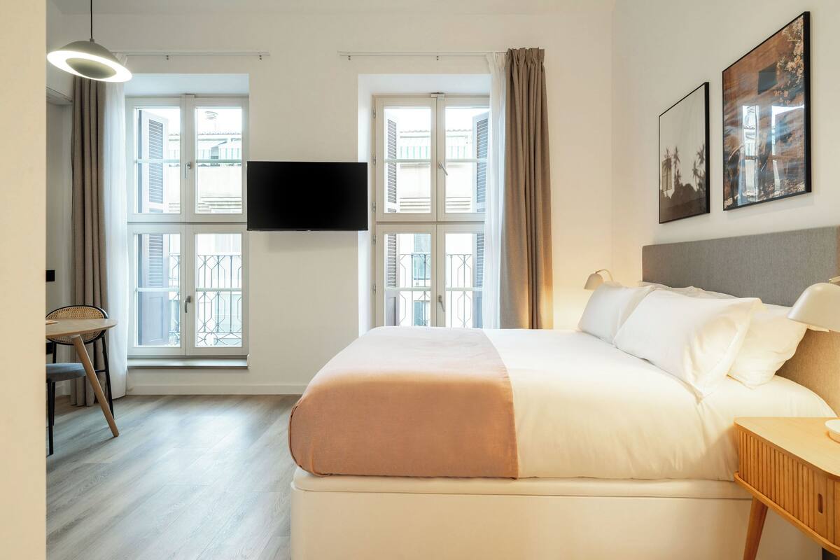 Ein Hotelzimmer mit Bett, Schreibtisch und Fernseher.