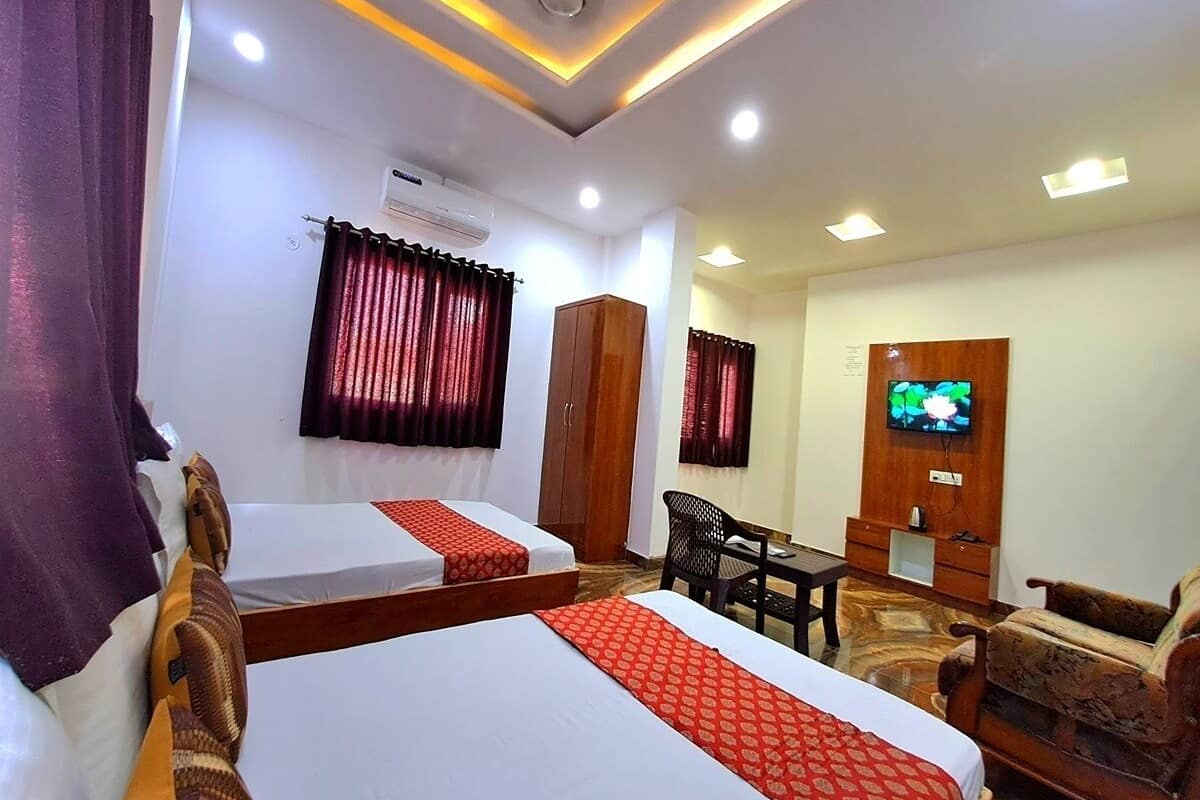 A hotel room with two beds, a TV, a desk, and a wardrobe.