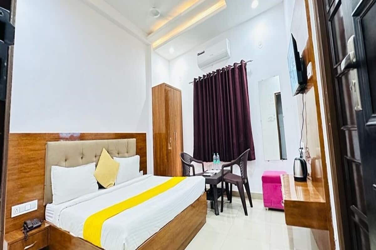 A hotel room with a bed, a desk, a chair, a wardrobe, and a television.