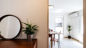 A modern kitchen with white cabinets, a dining area with a wooden table and chairs, and potted plants. - Casa La Palmetta by Wonderful Italy (Bari)