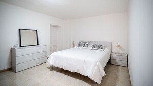 A bedroom with a bed, bedside tables, a dresser, a mirror, and a door. - Casa La Palmetta by Wonderful Italy (Bari)