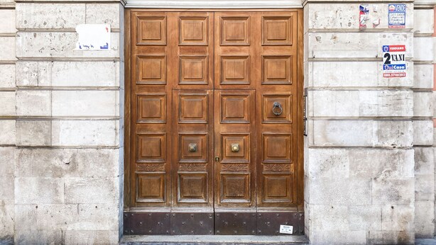 A large wooden double door with a metal handle, set in a stone building with a decorative arch above. - Casa La Palmetta by Wonderful Italy (Bari)