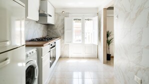A modern kitchen with white appliances, a marble backsplash, and a view to the outside. - Casa La Palmetta by Wonderful Italy (Bari)