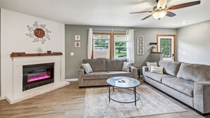 A living room with a fireplace, two sofas, a coffee table, and a ceiling fan.