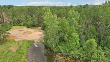 A forested area with a dirt path leading to a small dock over a body of water.