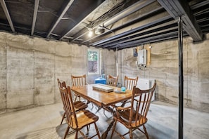 A room with a concrete wall, a wooden table with chairs, a window, and a white heater. - Fawn Lake Cottage for Families Looking for Privacy (Wisconsin Dells)