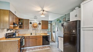 A kitchen with wooden cabinets, a black refrigerator, and a tiled backsplash.