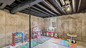 A playroom with a concrete floor, a window, and various children's play equipment.