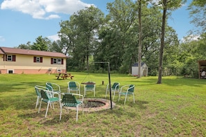 A backyard with a fire pit, green chairs, a picnic table, and a small shed. - Fawn Lake Cottage for Families Looking for Privacy (Wisconsin Dells)